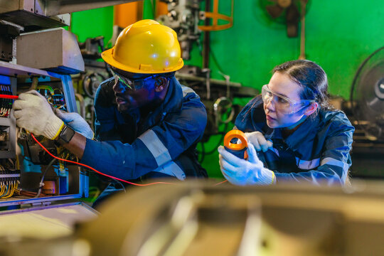 Factory technician inspecting electrical control cabinet in industrial plant
