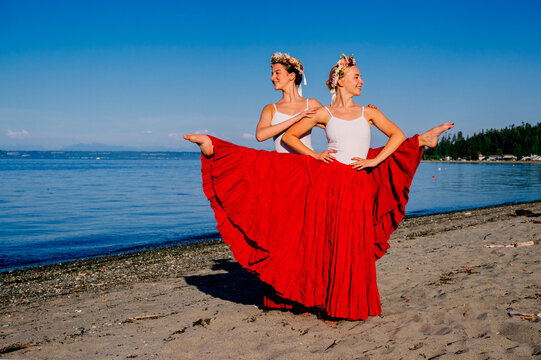 Two white women performing partner acrobatics on a beach in wa USA