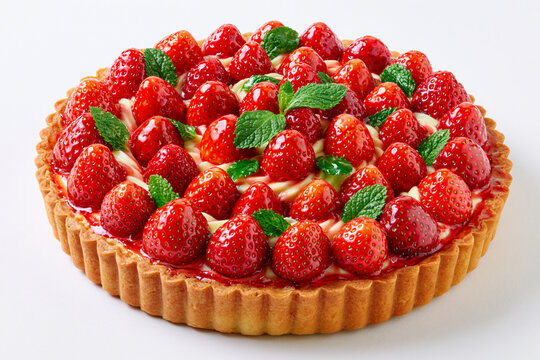 Tarte aux fraises sur fond blanc, p&acirc;te sabl&eacute;e dor&eacute;e, cr&egrave;me p&acirc;tissi&egrave;re et fraises fra&icirc;ches brillante en cercles concentriques, avec feuilles de menthe