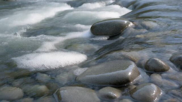 Crystal-clear river water flowing over stones for World Water Day campaigns, freshwater ecology studies, and corporate sustainability reports. Professional stock footage.