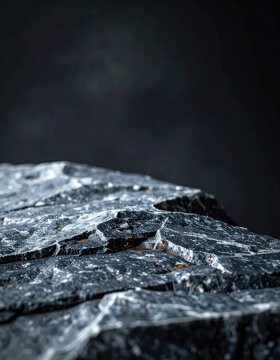 A close-up view of rough, textured dark gray rock with white and orange mineral deposits.