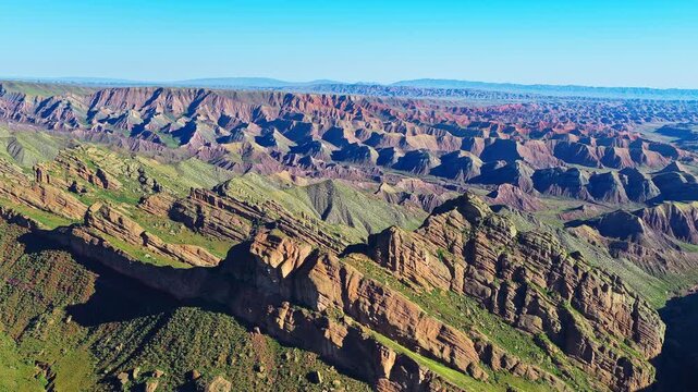 Aerial view of a colorful mountain range with unique geological formations and green valleys along the scenic S101 highway in Xinjiang, China