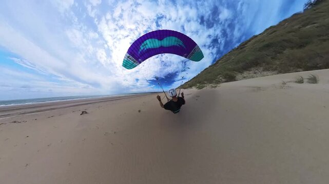 Thrilling rear POV of paraglider soaring real close to vegetated Dutch dunes