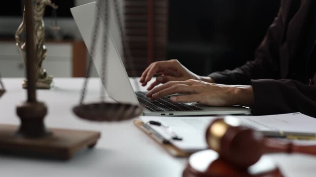 Professional lawyer typing on laptop at desk with scales of justice, gavel and legal documents, offering online law consultation and advice in modern courthouse or law firm