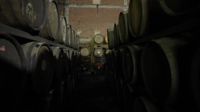 Long aisle of wooden barrels stored inside a rum aging warehouse, backdrop ready for text