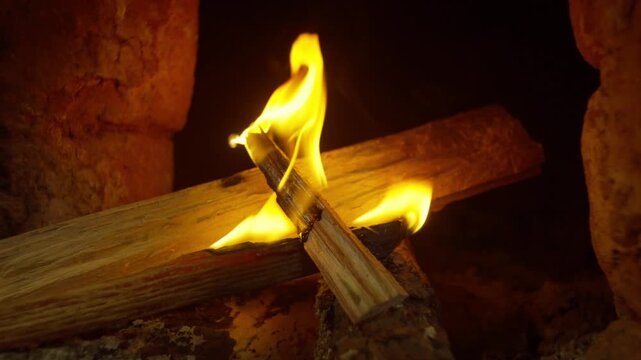 Burning firewood inside traditional kiln used for firing handmade clay Catrina figures, slow motion flames dance as the wood catches