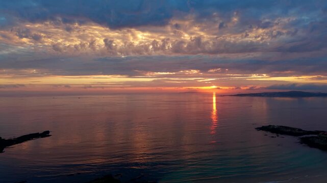 Golden sunset burning across cloud and calm water off A Lanzada beach in Sanxenxo Galicia