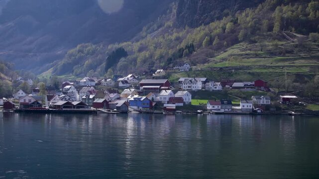 Scenic Undredal village with colorful houses reflected in calm Norway fjord waters, surrounded by hills