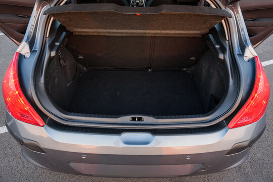 Open trunk of a modern gray hatchback car showing empty luggage compartment and cargo space in a parking lot.