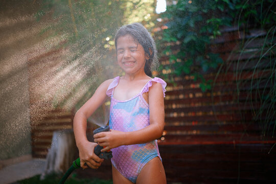 Girl Playing with Garden Hose Outdoors
