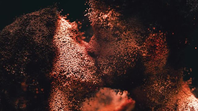 Luminous orange particles swirling in darkness, gradually coalescing to form the tender and intimate portrait of a man and woman kissing