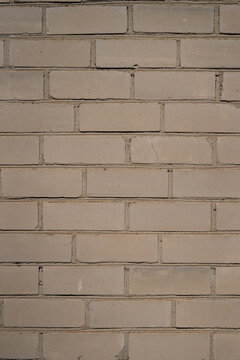 Textured beige brick wall with horizontal and vertical mortar lines, uniform pattern visible