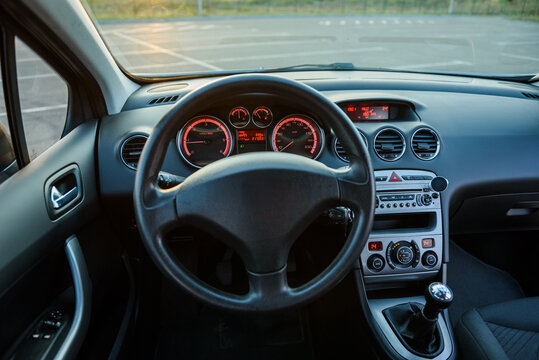 Front view of car dashboard and steering wheel from inside. Modern vehicle interior cockpit with instrumental panel and center console.
