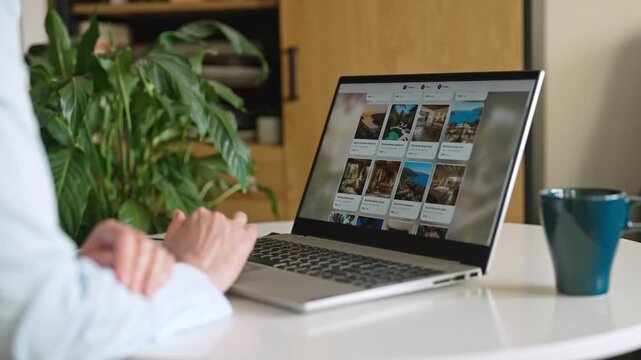 Person booking accommodation online using laptop at home desk.