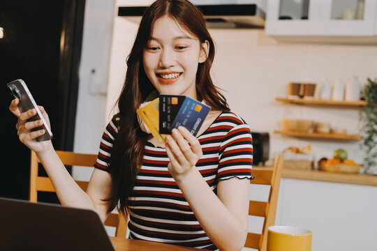 Happiness Entrepreneur beautiful business asian young woman wear casual use mobile phone for shopping online enjoy with social media and laptop at home.Small Business Startup.online banking