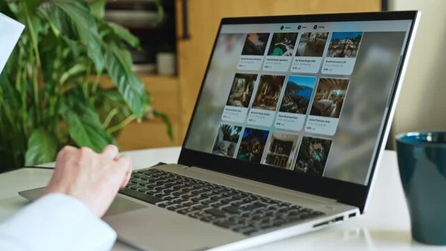 Person booking accommodation online using laptop at home desk.