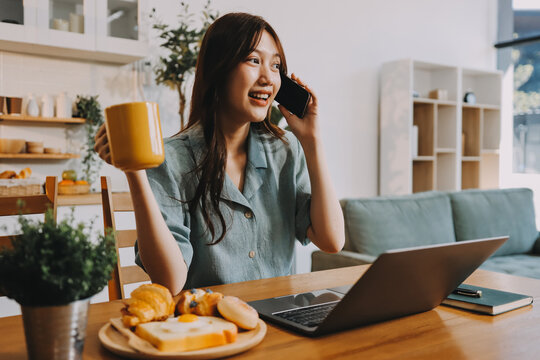 Happiness Entrepreneur beautiful business asian young woman wear casual use mobile phone for shopping online enjoy with social media and laptop at home.Small Business Startup.online banking