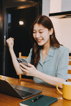 Happiness Entrepreneur beautiful business asian young woman wear casual use mobile phone for shopping online enjoy with social media and laptop at home.Small Business Startup.online banking
