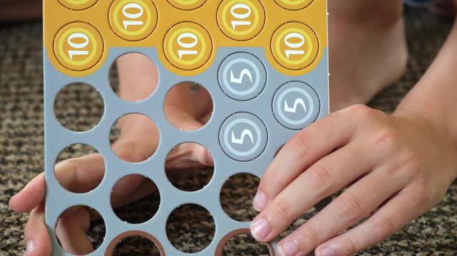Child hands pressing out cardboard game tokens with one, five and ten nominal value. Numbers toys coins. Board game components, hobby activities, early development. High quality 4k footage.
