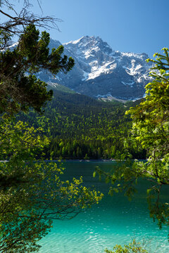 Travel landscape of Zugspitze Alps in Bavaria Germany, scenic summer nature panorama with forest, Eibsee lake, snow mountains peak. Alpine landscape