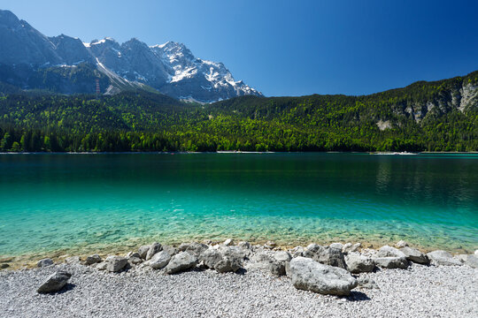 Travel landscape of Zugspitze Alps in Bavaria Germany, scenic summer nature panorama with forest, Eibsee lake, snow mountains peak. Alpine landscape