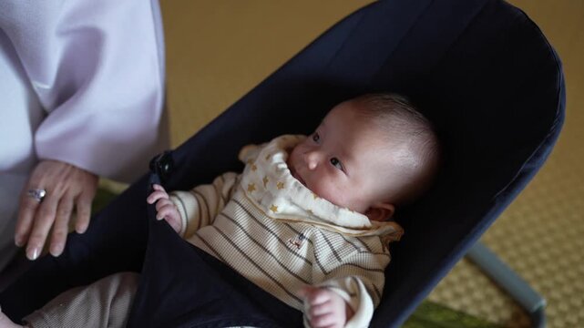 Soft light illuminates a quiet moment. Baby rests calmly in a dark cradle. Gentle hands hover nearby, offering comfort. Calm eyes gaze softly, curious and peaceful. Ideal for newborn scenes