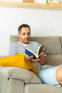 Man relaxing at home reading a book on sofa