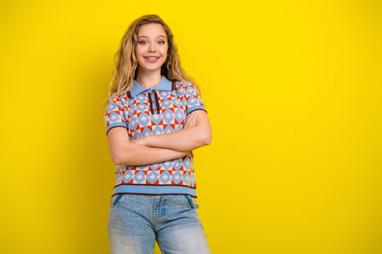 Smiling teen girl with braces in casual patterned shirt standing confidently against a bright yellow background