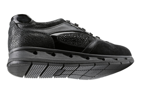 Women black mixed-media fashion sneaker isolated on white background. Casual running shoe with suede, patent leather and rhinestones, side bottom view.