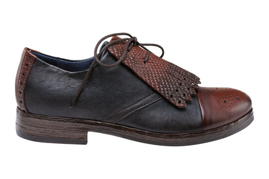 Women two-tone leather kiltie oxford shoes isolated on white background. Vintage style black and brown wingtip dress shoes with fringe, side view.