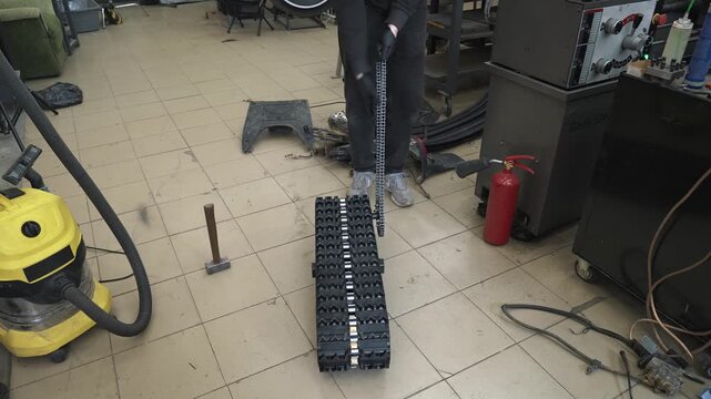 An engineer tightens the chain and checks the torque transmission on the track of a homemade snowmobile.