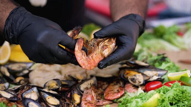 Fresh seafood. Fresh seafood is being cleaned and arranged with hands wearing gloves. The setting includes various shellfish and a mix of vegetables. 