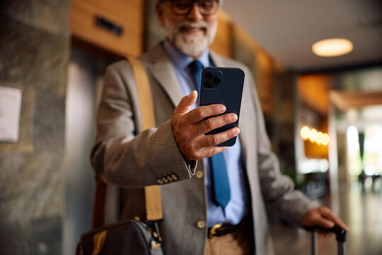 Close up of businessman using mobile phone in hotel lobby.