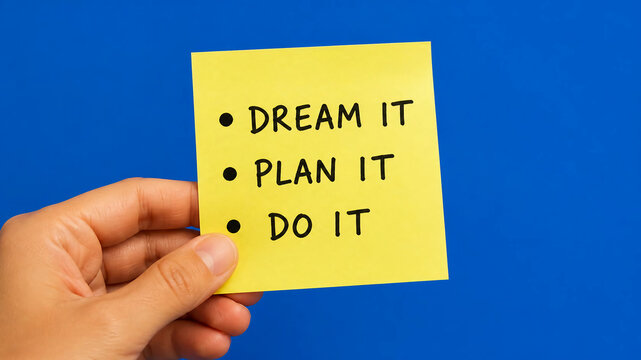A hand holding a yellow sticky note against a blue background, with the handwritten motivational text: "DREAM IT, PLAN IT, DO IT".