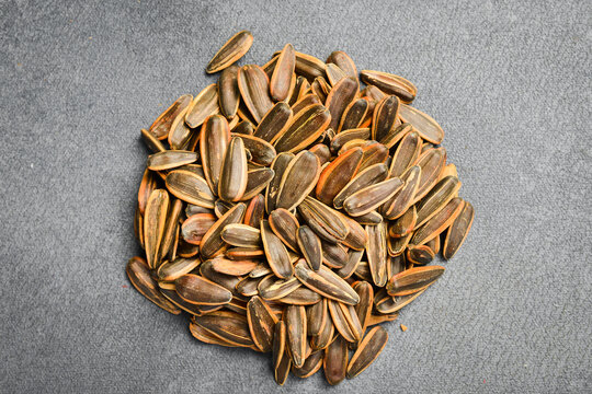 Striped sunflower seeds fill the entire frame as background texture. Healthy organic agricultural product ready for snack. Ideal image for food industry presentation background.