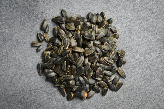 Natural black sunflower seeds piled on dark slate surface. Delicious vegan snack packed with healthy fats and nutrients. Great choice for organic farming background.