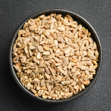 Peeled sunflower seeds are filled in a dark plate. They are ready to use as a cooking ingredient or snack. Top view from above.