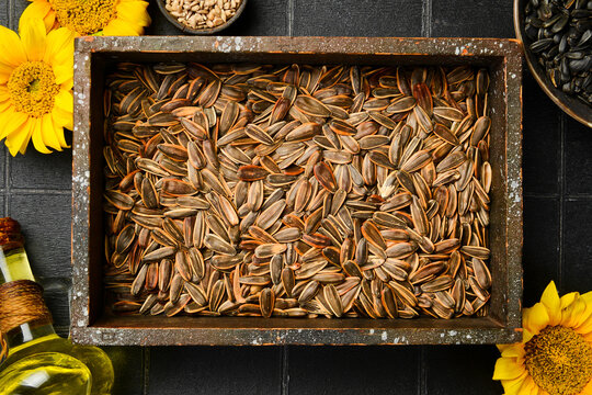 Natural sunflower seeds fill a vintage wooden box on a dark background surface. Nutritious vegan snack packed with healthy fats. Perfect choice for organic presentation.