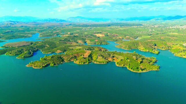 Stunning aerial footage of the Hel Peninsula, Poland, reveals lush greenery, winding peninsulas, and tranquil blue lakes framed by distant mountains and a sunlit sky. Dynamic drone video.