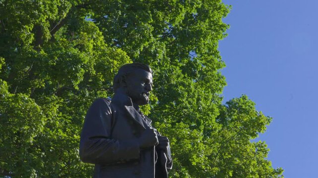 Center subject stays in frame while spinning around the statue from a low angle.