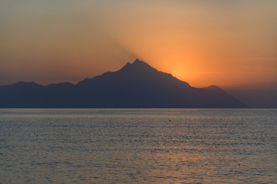Sun rising directly behind the peak of Mount Athos with golden rays across the Singitic Gulf, seen from Sithonia, Halkidiki, Greece
