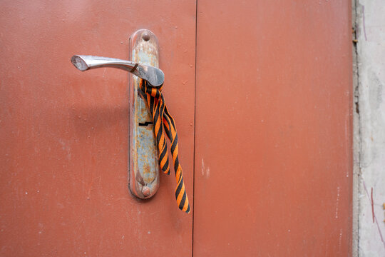 Striped ribbon of saint george tied to a metal door handle