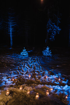 Enchanting winter night decor featuring glowing candles in glass cylinders set on pristine snow. A romantic atmosphere for weddings, marriage proposals, or winter celebrations.