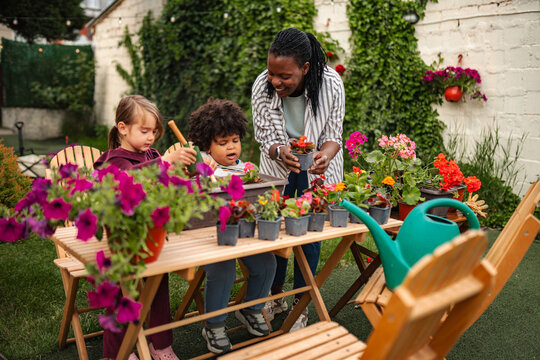 Mother and children learning gardening skills together in backyard