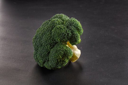 Fresh raw broccoli head on dark textured surface