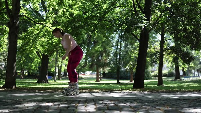 Woman carefully practices inline skating with small cautious movements showing the early learning stage as she builds confidence and balance on a quiet park path