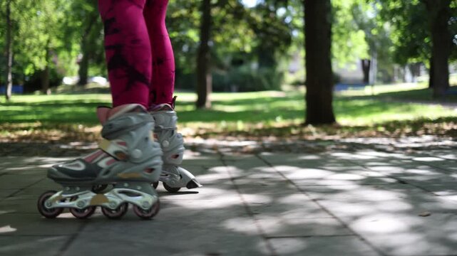 Close up of inline skates carving through a park path with smooth edge control and balanced technique during an outdoor roller fitness training session