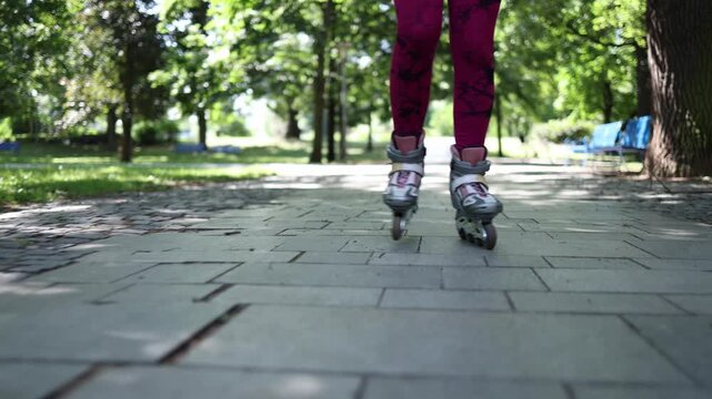 Close up of inline skates rolling across a smooth park path highlighting precise footwork steady balance and controlled technique during outdoor fitness training