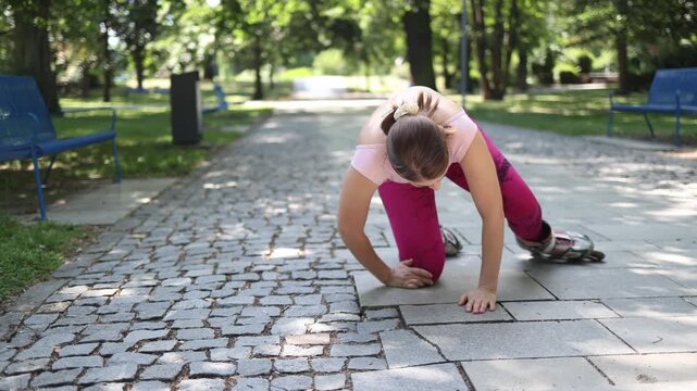 Woman falls during roller skating training grabbing her knee in pain after losing balance on uneven pavement highlighting sports injury risk outdoors