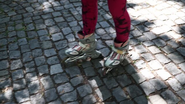 Close up of a woman carefully navigating inline skates across uneven cobblestones highlighting the challenge of finding smooth places for roller skating in many cities